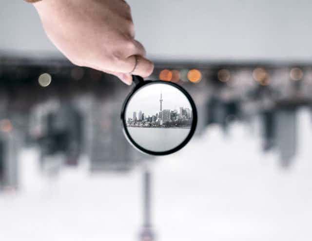 Blurred cityscape with part brought into focus by magnifying glass