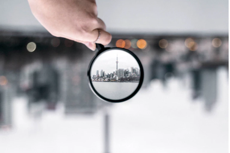 Blurred cityscape with part brought into focus by magnifying glass