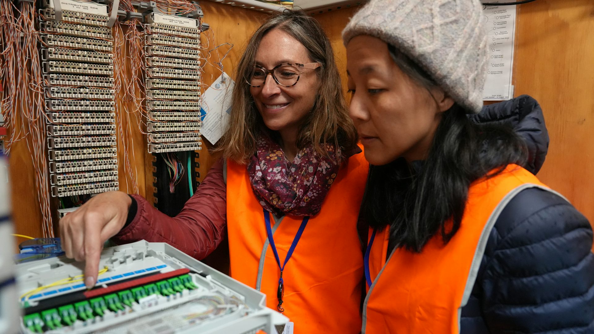 Two authors pointing to fibre optic cables used in the experiment.