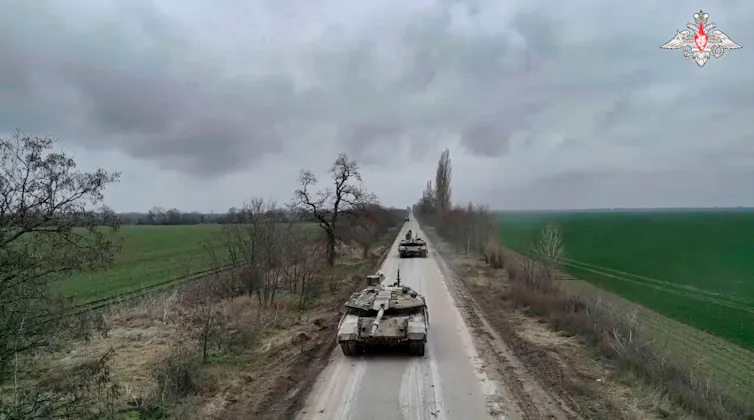 Two tanks drive down a country road.