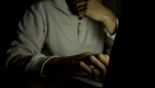 A man on a laptop in a dark room