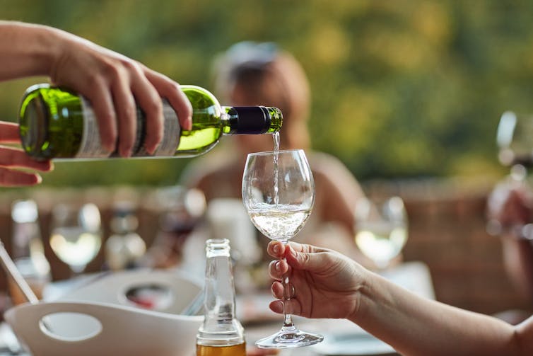 Person pours wine into a glass at a lunch