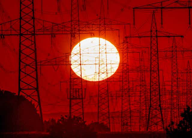 sun behind electricity towers