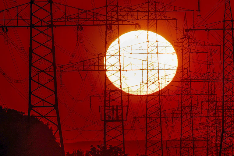 sun behind electricity towers