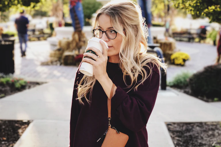 Woman walks, holding a coffee