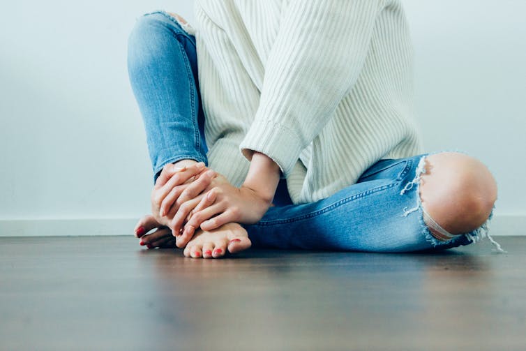 Woman in jeans sits, cross-legged