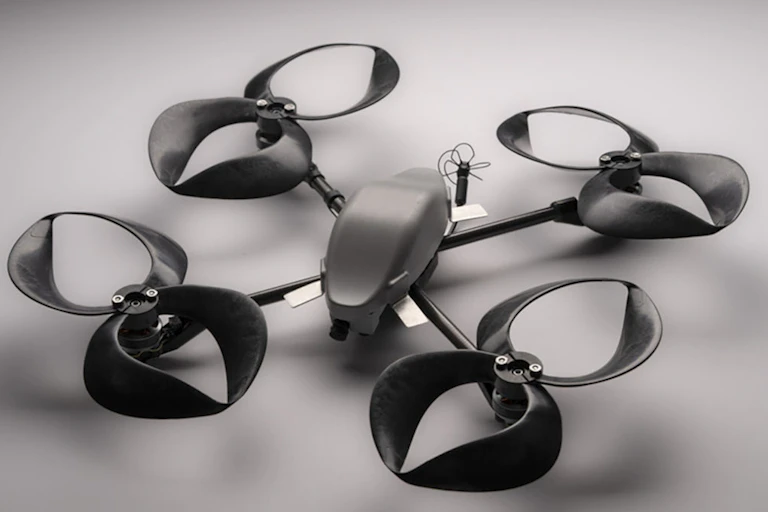 A black drone with four pinwheel shaped propellers with closed blades