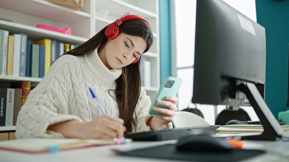 Jeune femme écrivant sur un ordinateur portable avec un smartphone étudiant dans une classe universitaire