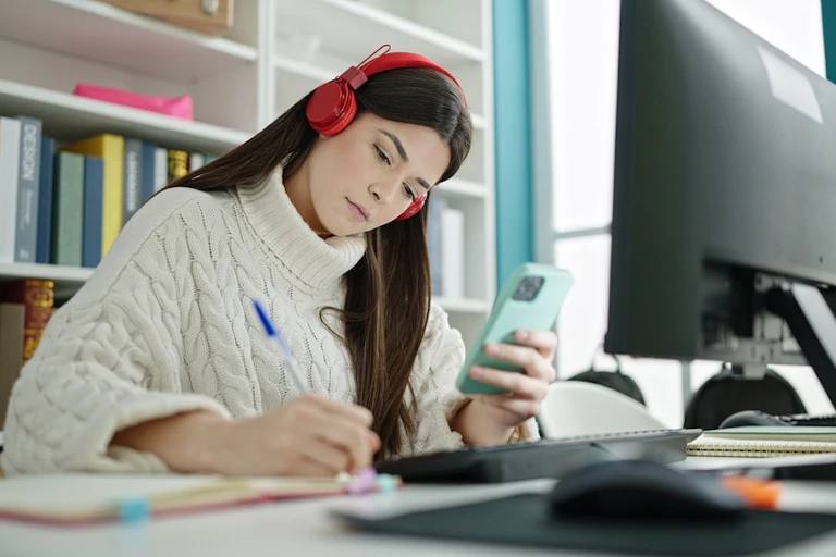 Jeune femme écrivant sur un ordinateur portable avec un smartphone étudiant dans une classe universitaire