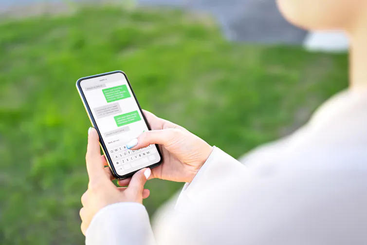 Femme envoyant des SMS avec son téléphone à l’extérieur