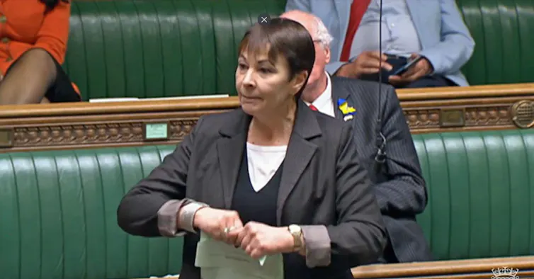 Caroline Lucas standing in parliament ripping a document in half.