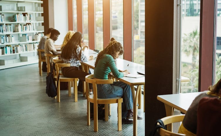 Jeune groupe d’étudiants qui étudient ensemble dans une bibliothèque universitaire
