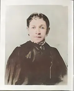 Retrato de una mujer a finales del siglo diecinueve, vestida de negro y mirando a cámara.