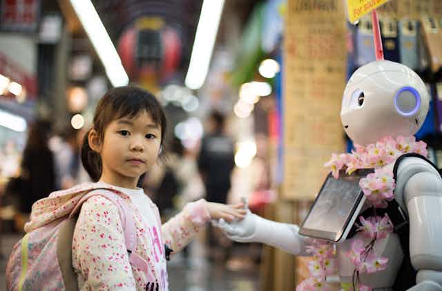 petite fille donne la main à un robot humanoïde