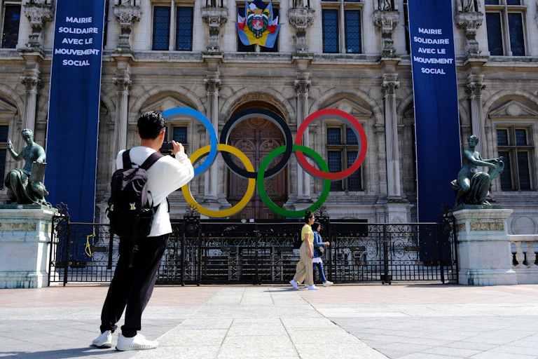Un homme prend en photo le logo des Jeux olympiques installé devant l'Hotel de ville de Paris