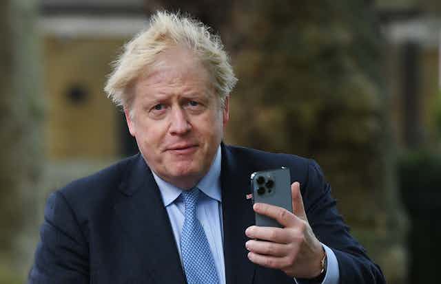 Boris Johnson holding a phone.
