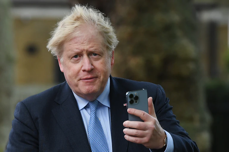 Boris Johnson holding a phone.