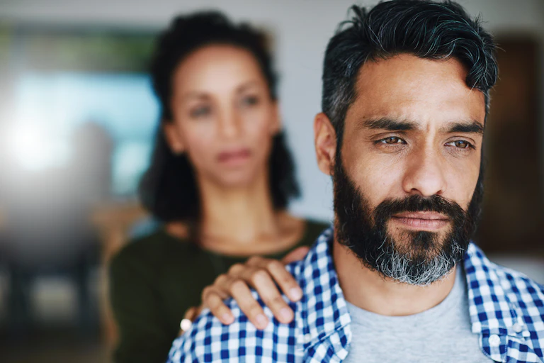 A woman puts her hand on the shoulder of her distraught husband.