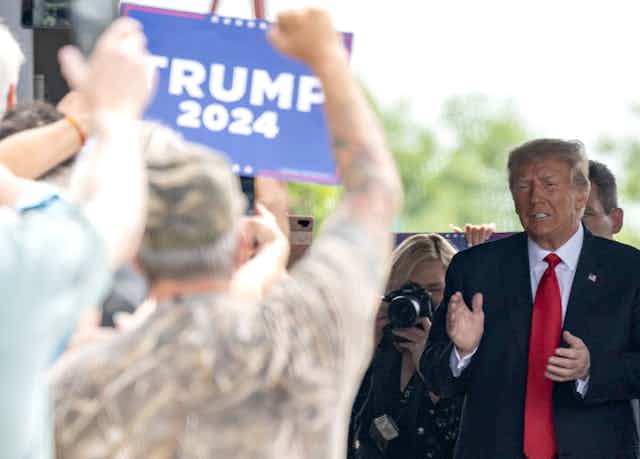 Donald Trump salue des personnes brandissant des pancartes « Trump 2024 »