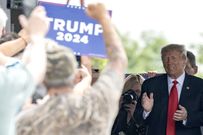 Donald Trump salue des personnes brandissant des pancartes « Trump 2024 »