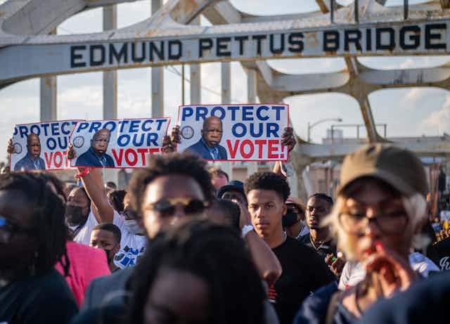 A group of black people are marching across a bridge in order to protect voting rights.