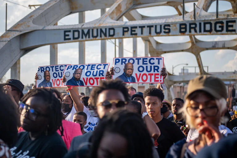 A group of black people are marching across a bridge in order to protect voting rights.