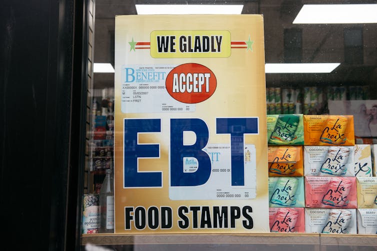 A sign in a grocery store window says 'We gladly accept EBT food stamps.'