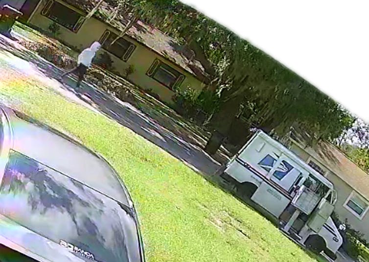 A person in a white hooded sweatshirt walks toward a U.S. postal carrier