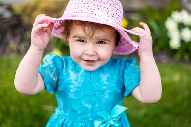 Toddler girl in blue dress and pink hat