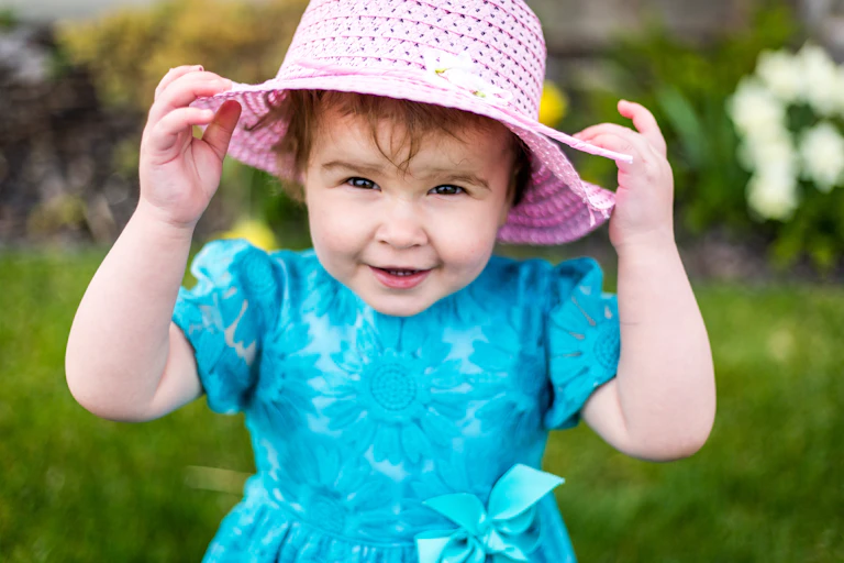 Toddler girl in blue dress and pink hat