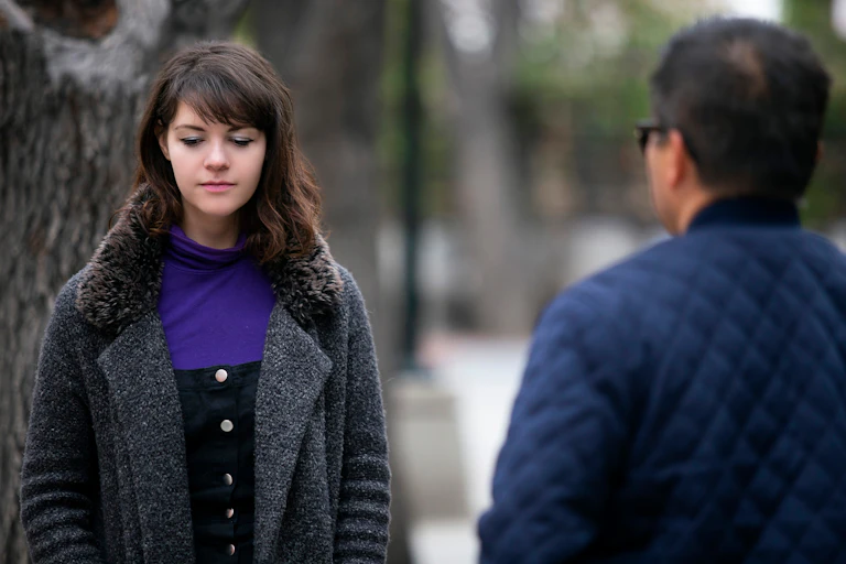 woman walks with eyes down while stanger talks to her
