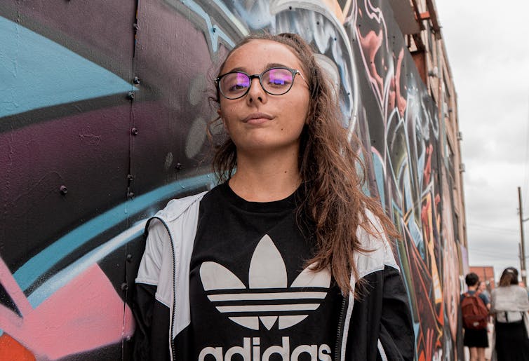 Girl walks past graffiti wall with head held high