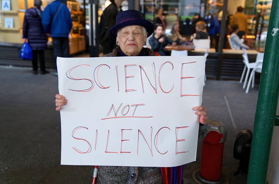 Menyw yn dal arwydd sy'n dweud 'science not science'.