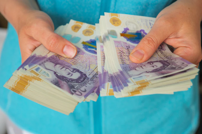 Woman counting out a wad of £20 notes