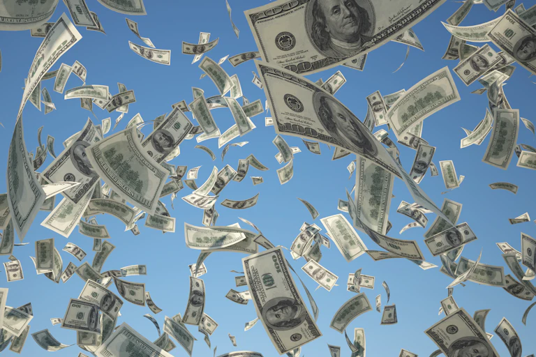100 US Dollar, bills flying on blue sky background.