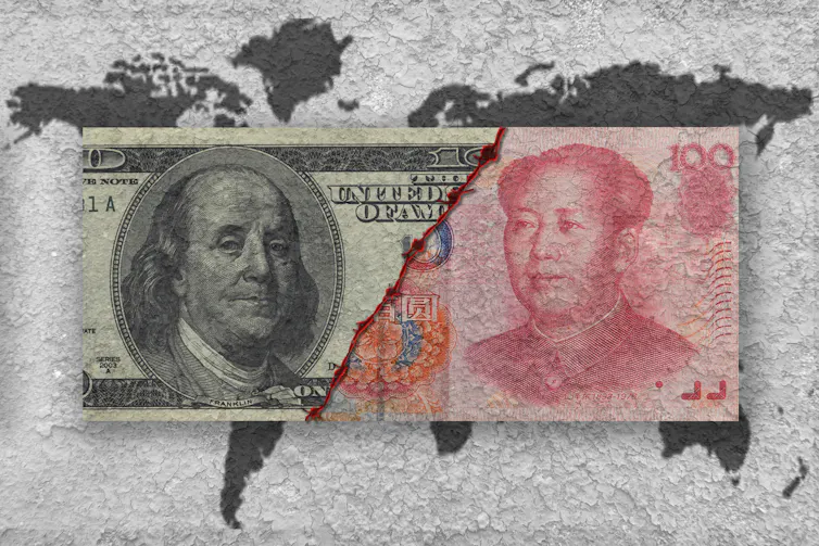 Full-colour US dollar and Chinese yuan notes torn in half and pictured beside each other over a grey map of the world.