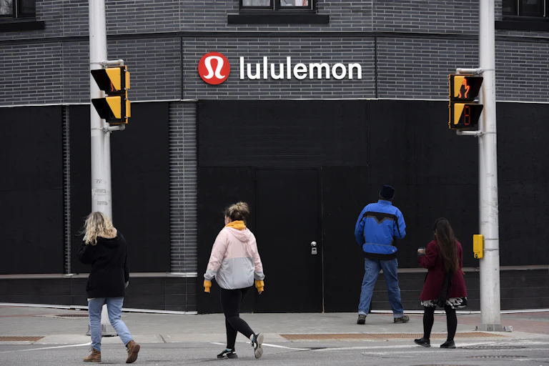 People cross the street in front of a Lululemon store.
