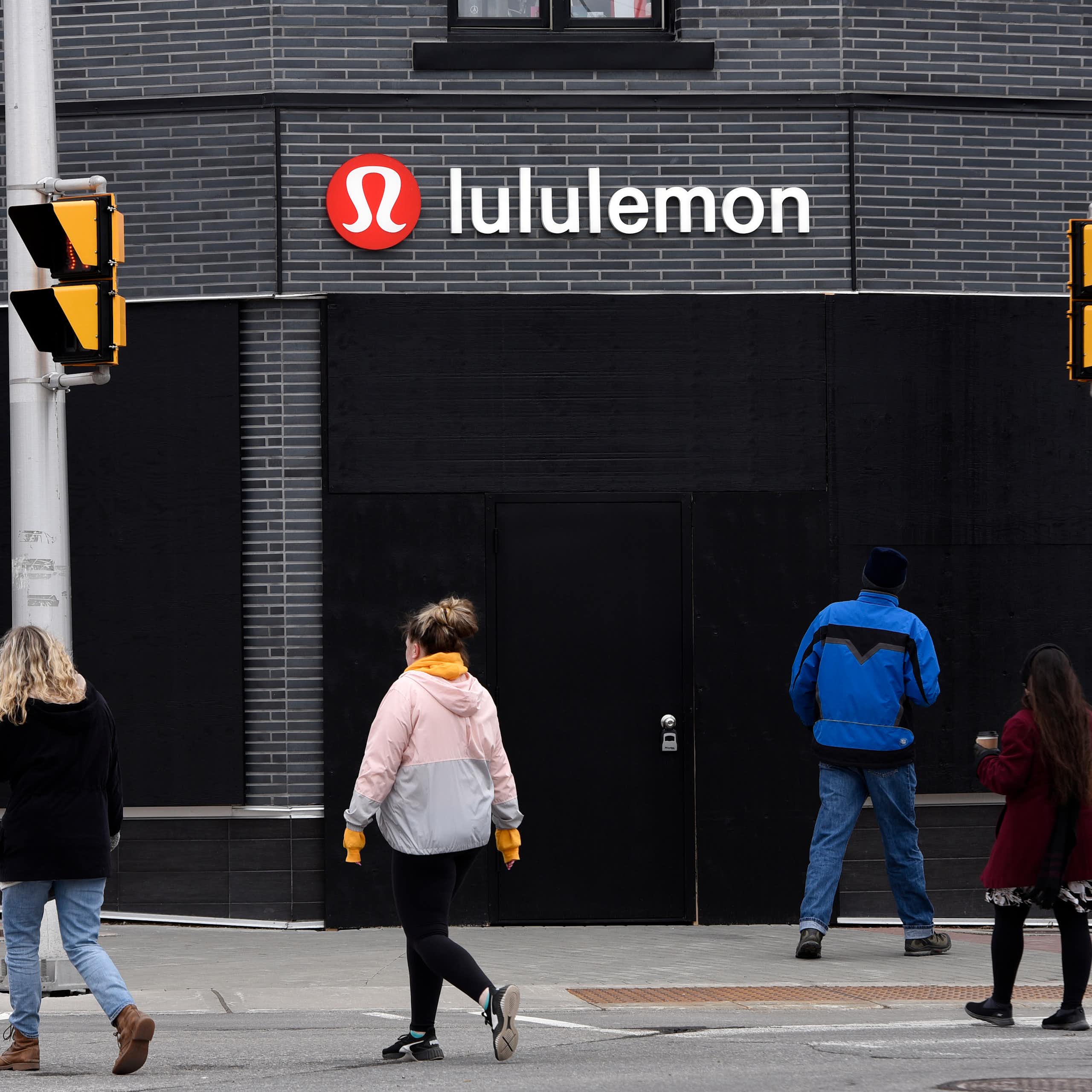 People cross the street in front of a Lululemon store.