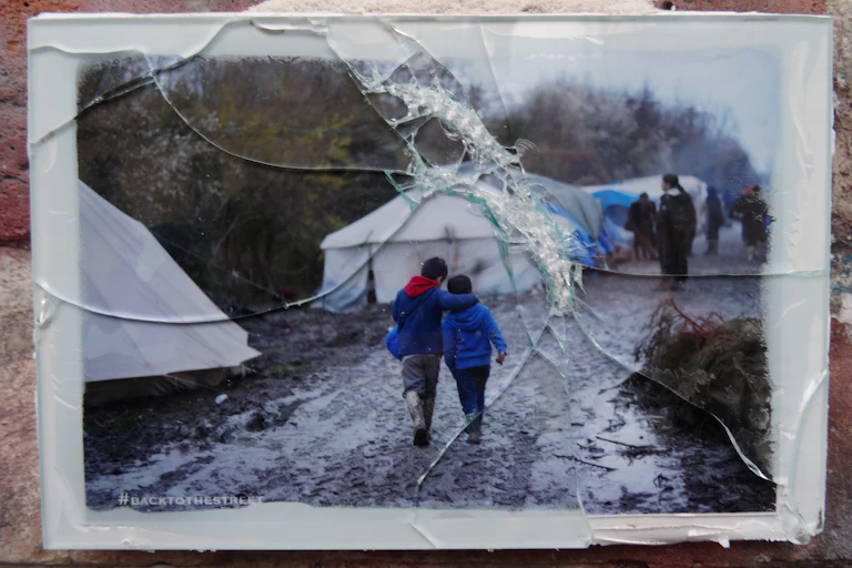 Deux enfants marchent dans une rue boueuse.