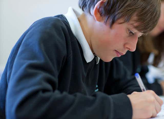 Boy in school uniform writing with biro
