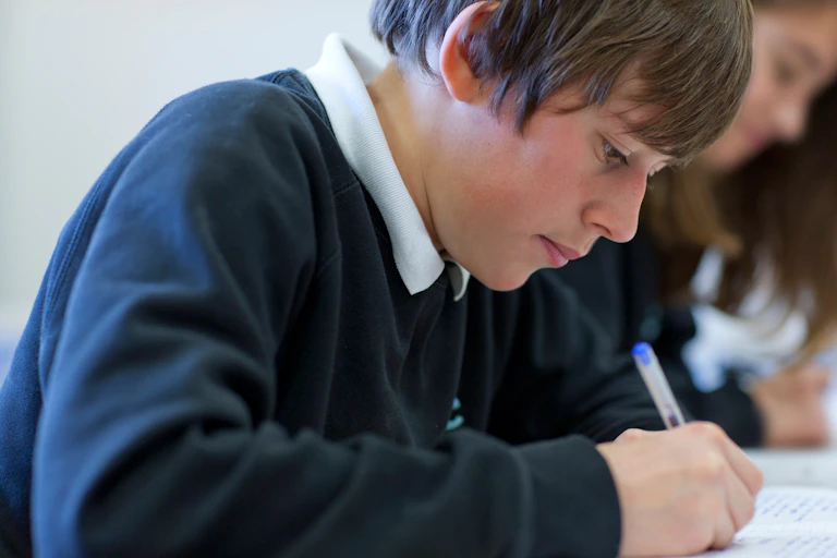 Boy in school uniform writing with biro