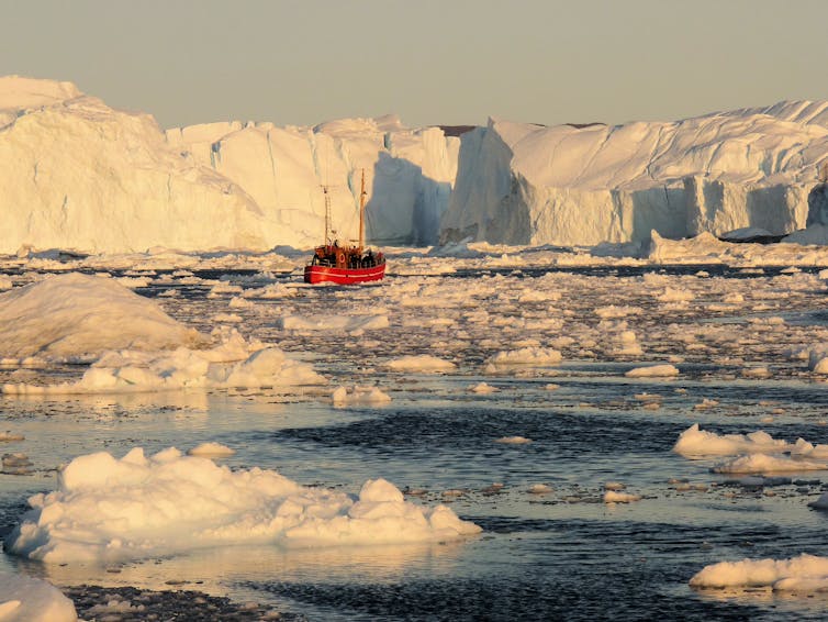 A fishing boat surrounded by icebergs that have come off a glacier.