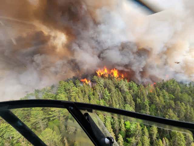 The orange flames of a wildfire and billowing brown smoke is seen from above