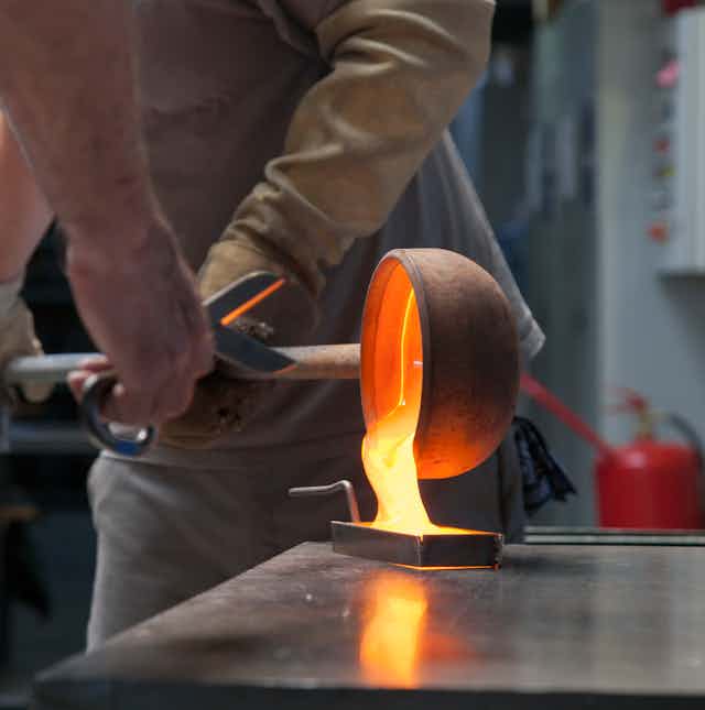 A man pouring molten glass into a mould.