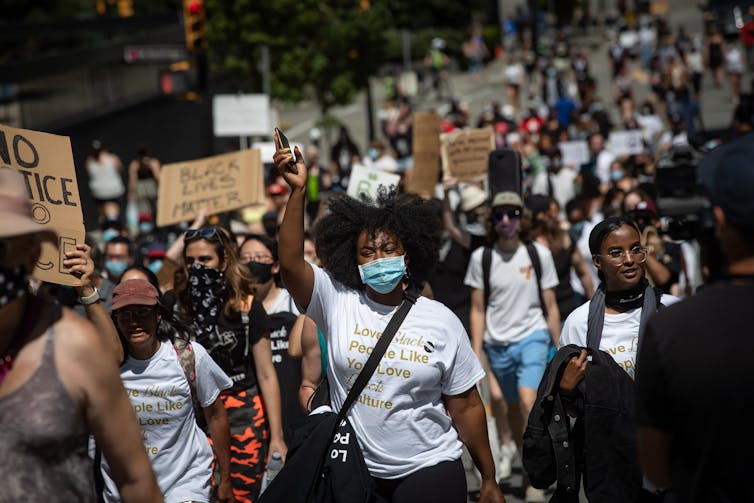 A group of people march while holding signs in support of Black Lives Matter and racial equality.