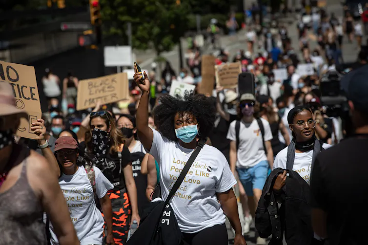 A group of people march while holding signs in support of Black Lives Matter and racial equality.