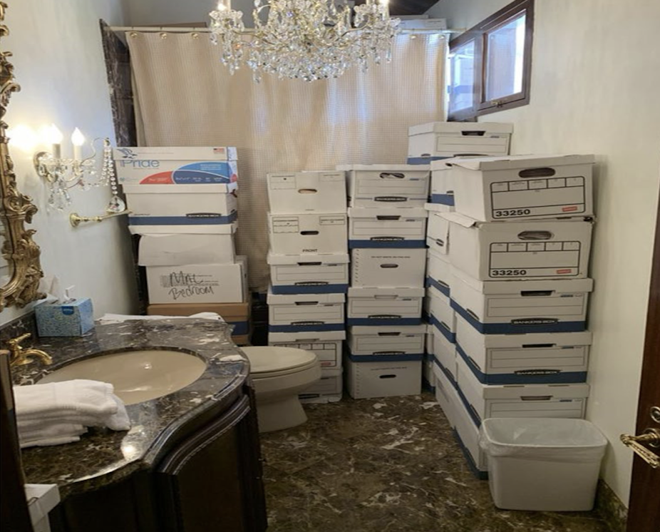 White, lidded boxes containing classified documents are stacked around a toilet and shower in a bathroom. 
