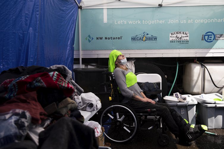 A woman in a wheel chair leans back with cooling clothes on her forehead and chest during the 2021 Pacific Northwest heat wave. The heat wave killed hundreds of people.