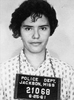 Black and white mugshot photo of woman with short hair.