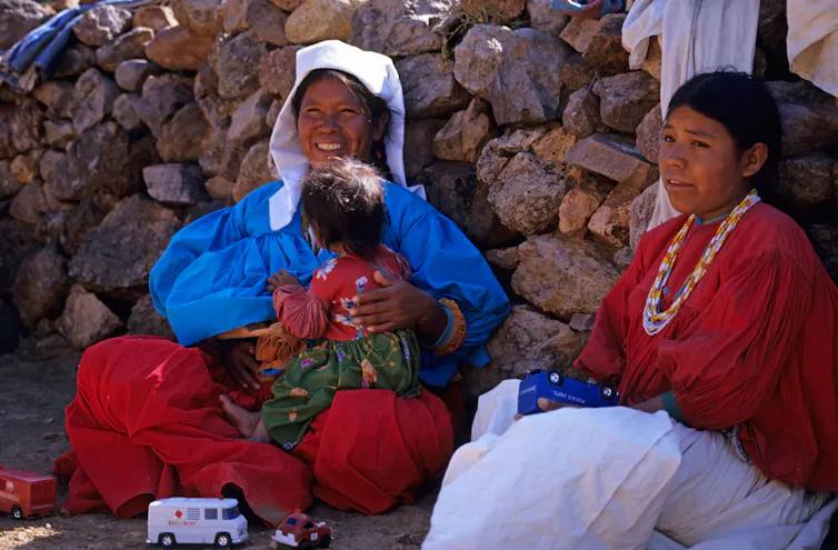 Two women in traditional dress with a baby.